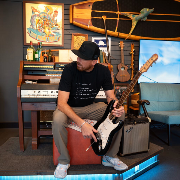 Man wearing Men's Lost Boy Definition Tee performing on stage with guitar | Lost Boy Creations Key West 