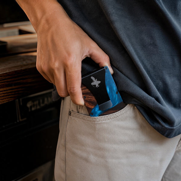 Wood and Epoxy Cash Clip Card Holder in Blue — lifestyle shot, pulling card holder from front pocket | Lost Boy Creations Key West