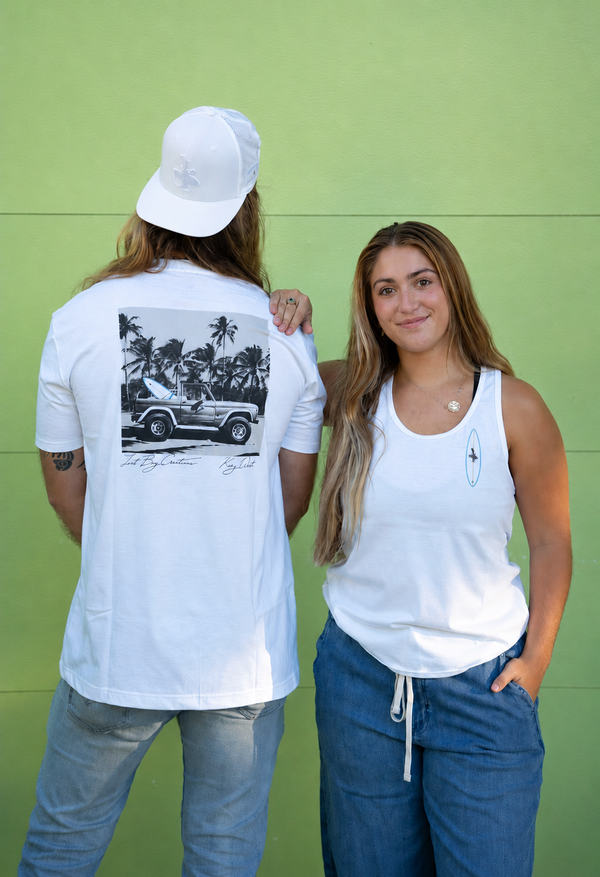 Men's Bronco Tee 2.0 in White — lifestyle back shot, Bronco graphic with palm trees and "Lost Boy Creations Key West" script, Female model in white, tank top, with Surfboard Lost Boy Creations Logo on chest| Lost Boy Creations Key West