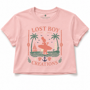Women's Cropped Beach Day Tee in Dusty Blush — graphic front flat lay, Lost Boy Creations vintage Key West surfer scene with palm trees, sailboat, anchor, and seashells | Lost Boy Creations Key West