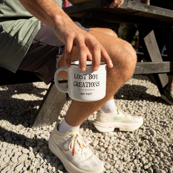 Person holding Lost Boy Creations ceramic mug left handle facing out on a picnic table lifestyle shot | Lost Boy Creations Key West