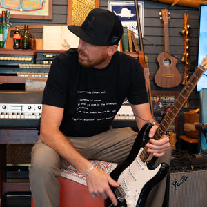 Man playing a guitar in a store with black t-shirt