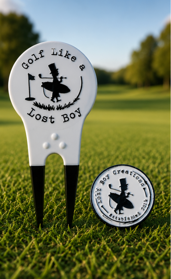 LBC Divot Tool in White/Black — lifestyle shot on golf course, tool standing upright in ground, ball marker placed to the side | Lost Boy Creations Key West