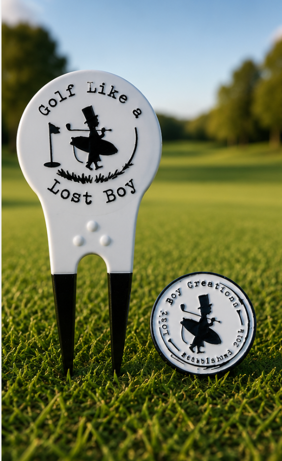 LBC Divot Tool in White/Black — lifestyle shot on golf course, tool standing upright in ground, ball marker placed to the side | Lost Boy Creations Key West