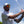 LBC Golf Polo white lifestyle shot worn by man mid golf swing outdoors with all-over surfer silhouette and star pattern and LBC trucker hat | Lost Boy Creations Key West