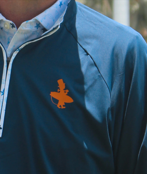 LBC Golf 1/4 Zip navy lifestyle close-up of orange Lost Boy surfer silhouette logo on chest with Key West vibe patterned collar visible | Lost Boy Creations Key West