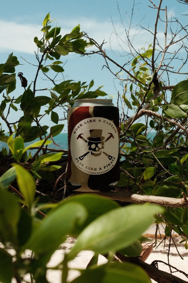 Lost Boy Koozie - Pirate 2.0 in Camo — lifestyle shot, white skull and crossbones pirate graphic, mangrove and beach background | Lost Boy Creations Key West
