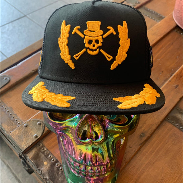 A Pirate's Life for Me Hat in Black — styled on iridescent skull display, yellow pirate skull & crossbones emblem, gold laurel wreath on front & brim | Lost Boy Creations Key West