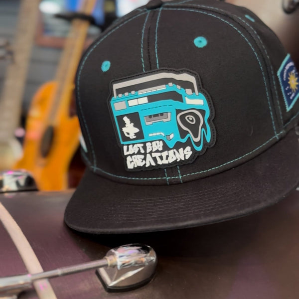 Lost Boy Creations Ghetto Blaster black snapback hat with a teal boombox rubber patch and matching contrast stitching.