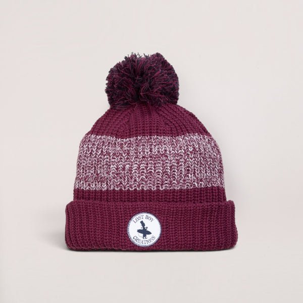 Lost Boy Creations burgundy pom pom beanie with a chunky knit gradient design and signature circular brand patch.
