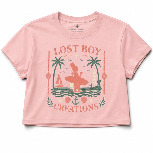 Lost Boy Creations dusty blush cropped beach tee with a vintage Key West surfer and palm tree graphic print.