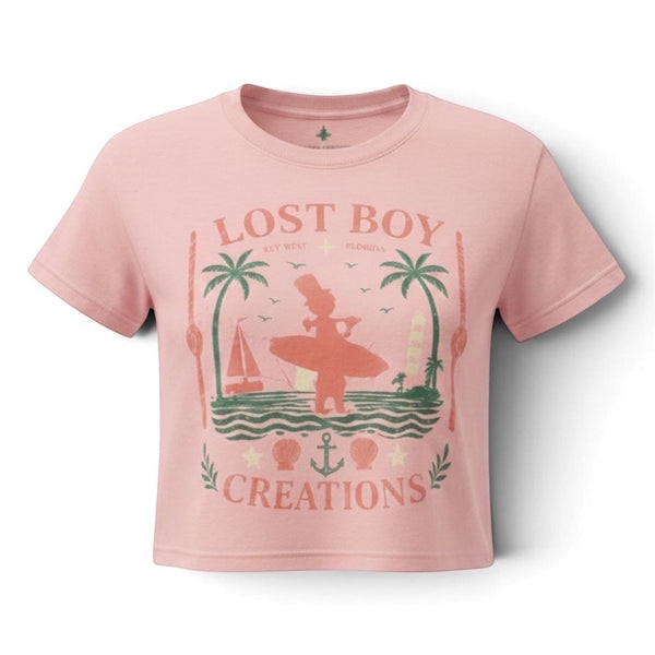 Lost Boy Creations dusty blush cropped tee with a vintage Key West coastal surfer graphic in soft sun-faded tones.