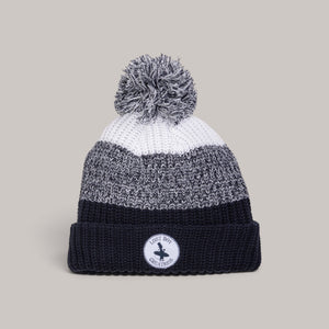Lost Boy Creations pom pom beanie featuring a chunky knit gradient design in white, grey, and navy with a logo patch.