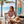 Women's Surfing Club Ringer Tee Desert Pink ringer tee worn by model seated at beachside table with surfboard and palm trees | Lost Boy Creations Key West