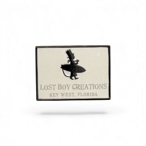 LBC Collectible Pin white and black enamel pin with Lost Boy surfer silhouette and Lost Boy Creations Key West Florida text | Lost Boy Creations Key West