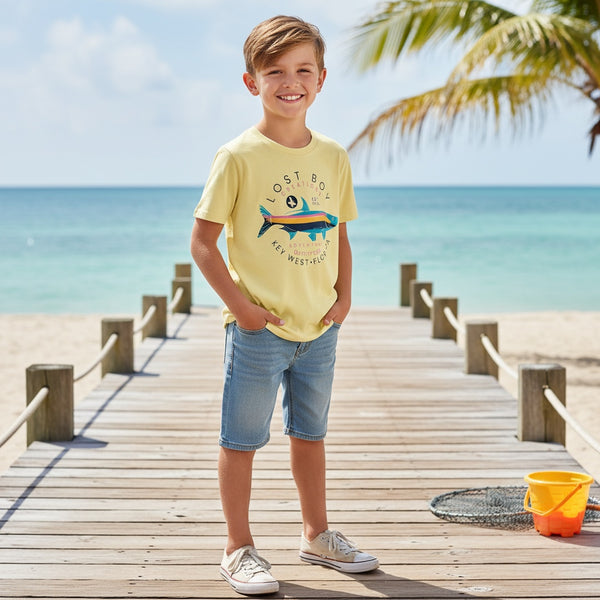 Kid's Silver King Tee lemon yellow lifestyle shot worn by boy on a wooden pier with tropical beach backdrop and colorful tarpon graphic | Lost Boy Creations Key West
