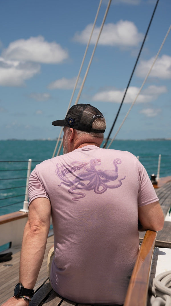 Men's Octopus Tee 2.0 in Purple — on-model back view, man sitting on sailboat wearing octopus graphic tee | Lost Boy Creations Key West